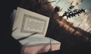 Otwarta księga w trawie, pełna motywujących cytatów biblijnych, przypomina o wolności ducha.