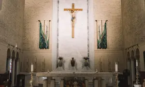 Ołtarz w kościele z krzyżem i obrazem Jezusa. W tle wiszą ozdobne banery, a na ołtarzu stoją świece i wazony. Idealne miejsce do wyboru imiona do bierzmowania.