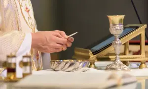 Kapłan trzyma opłatek, przygotowując się do Eucharystii. Co to jest Eucharystia? To sakrament.