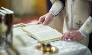 Dłoń duchownego trzyma księgę podczas nabożeństwa. Czas trwania rezurekcji jest nieznany, ale liturgia jest podniosła.