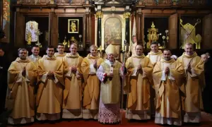 Biskup w otoczeniu młodych kapłanów w kościele.
