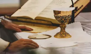 Złoty kielich i księgi liturgiczne na ołtarzu, przygotowanie do mszy. To moment, gdy wierni doświadczają cudu eucharystycznego.
