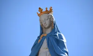 Posąg Matki Boskiej w koronie, symbolizujący czystość i idealizm, na tle błękitnego nieba.