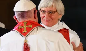Kobieta ksiądz w okularach uśmiecha się, obejmując papieża.
