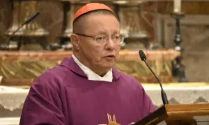 Biskup Ryś, w purpurowej szacie i z czerwoną piuską, przemawia przy mikrofonie, dzieląc się swoimi poglądami.