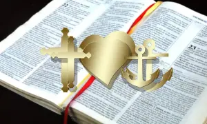 Złoty krzyż jerozolimski, serce i kotwica na otwartej Biblii. Symbol wiary, nadziei i miłości.
