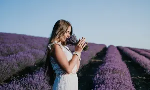 Kobieta w białej sukience wącha bukiet lawendy na polu, jakby słuchała słów z psalm 147.