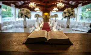 Otwarta Biblia na drewnianym stole, w tle udekorowana sala weselna. Symbolika 666 znaczenie w kontekście duchowym.