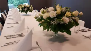 Elegancko nakryty stół na stypę, ozdobiony bukietami białych i kremowych róż.
