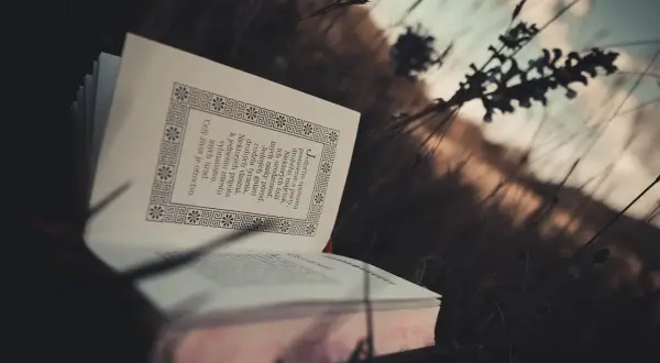 Otwarta księga w trawie, pełna motywujących cytatów biblijnych, przypomina o wolności ducha.