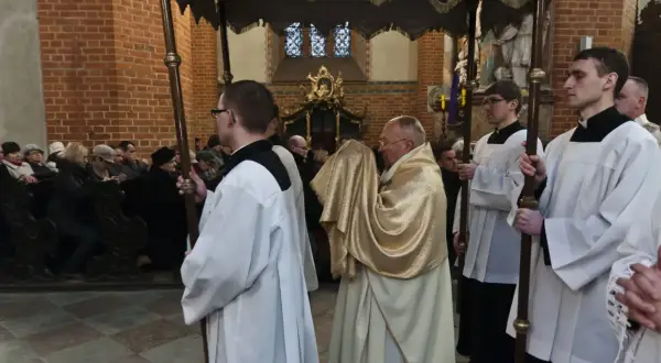 Uroczysta procesja w kościele, kapłan w złotej szacie niesie relikwie. To symboliczna rezurekcja.