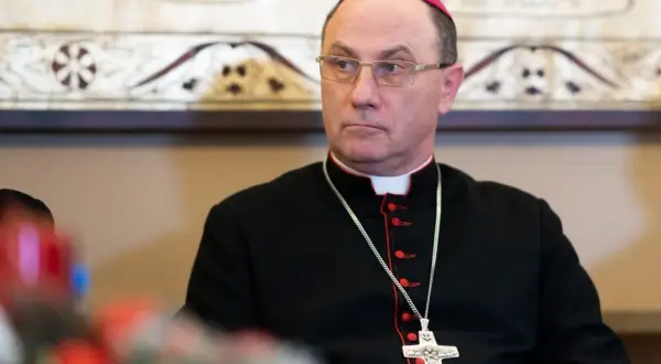 Prymas Polski w okularach i czarnej sutannie z krzyżem na łańcuszku.