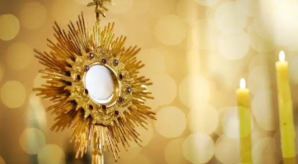 Złota monstrancja z hostią, otoczona płomieniami świec, symbolizuje nadzieję na odpust zupełny.