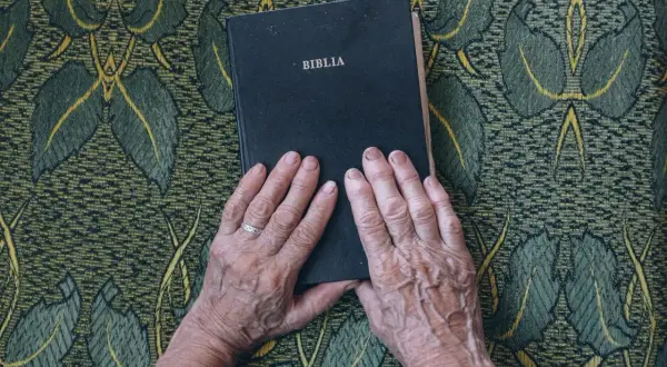 Dłonie starszej osoby spoczywają na Biblii. Kto napisał Stary Testament? To pytanie, na które odpowiedzi szukamy w tej księdze.