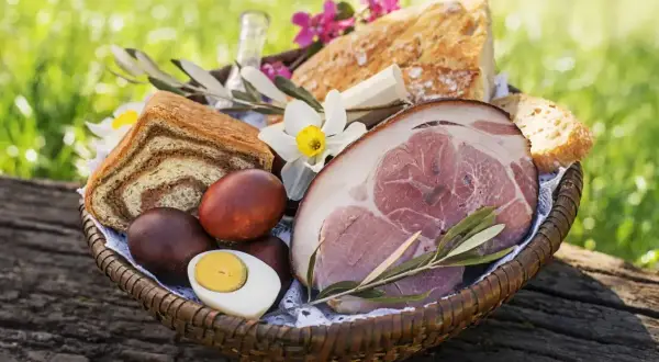 Koszyk z pieczonym mięsem, chlebem, jajkami i kwiatami. Czy w Wielką Sobotę można jeść mięso? Tradycyjnie nie, ale ten widok kusi!