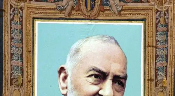 Portret Ojca Pio, jego ciało jest częściowo widoczne. Obraz ozdobiony jest bogatą ramą z motywami kwiatowymi i aniołkami.