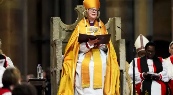 Arcybiskup Canterbury w złotej szacie i mitrze, siedzi na tronie, trzymając księgę.