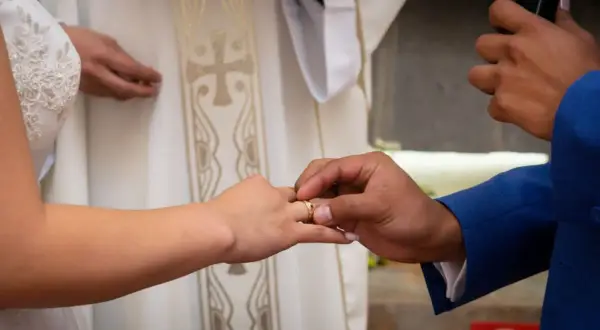 Pan młody zakłada obrączkę na palec panny młodej. Ceremonia ślubna, gdzie co Bóg złączył, niech człowiek nie rozdziela.