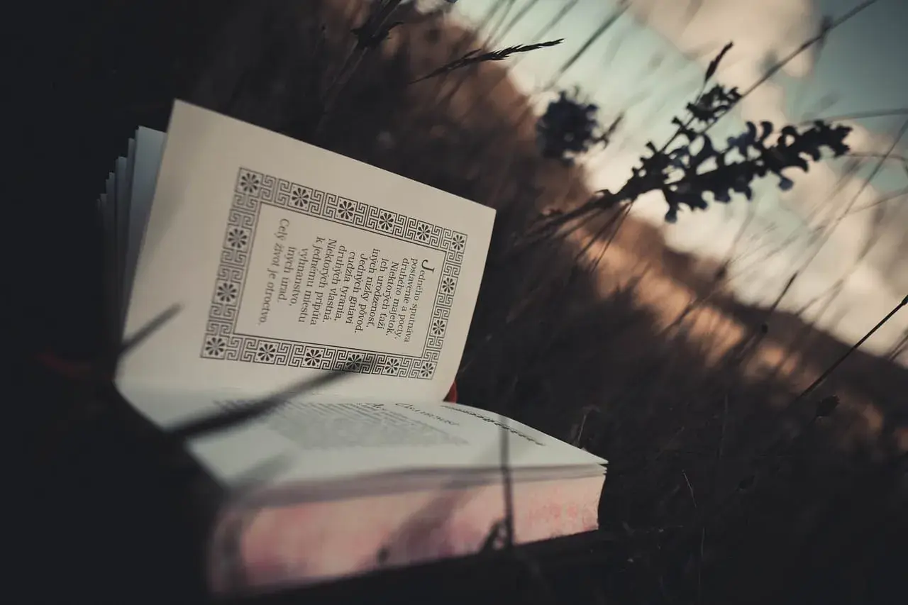 Otwarta księga w trawie, pełna motywujących cytatów biblijnych, przypomina o wolności ducha.