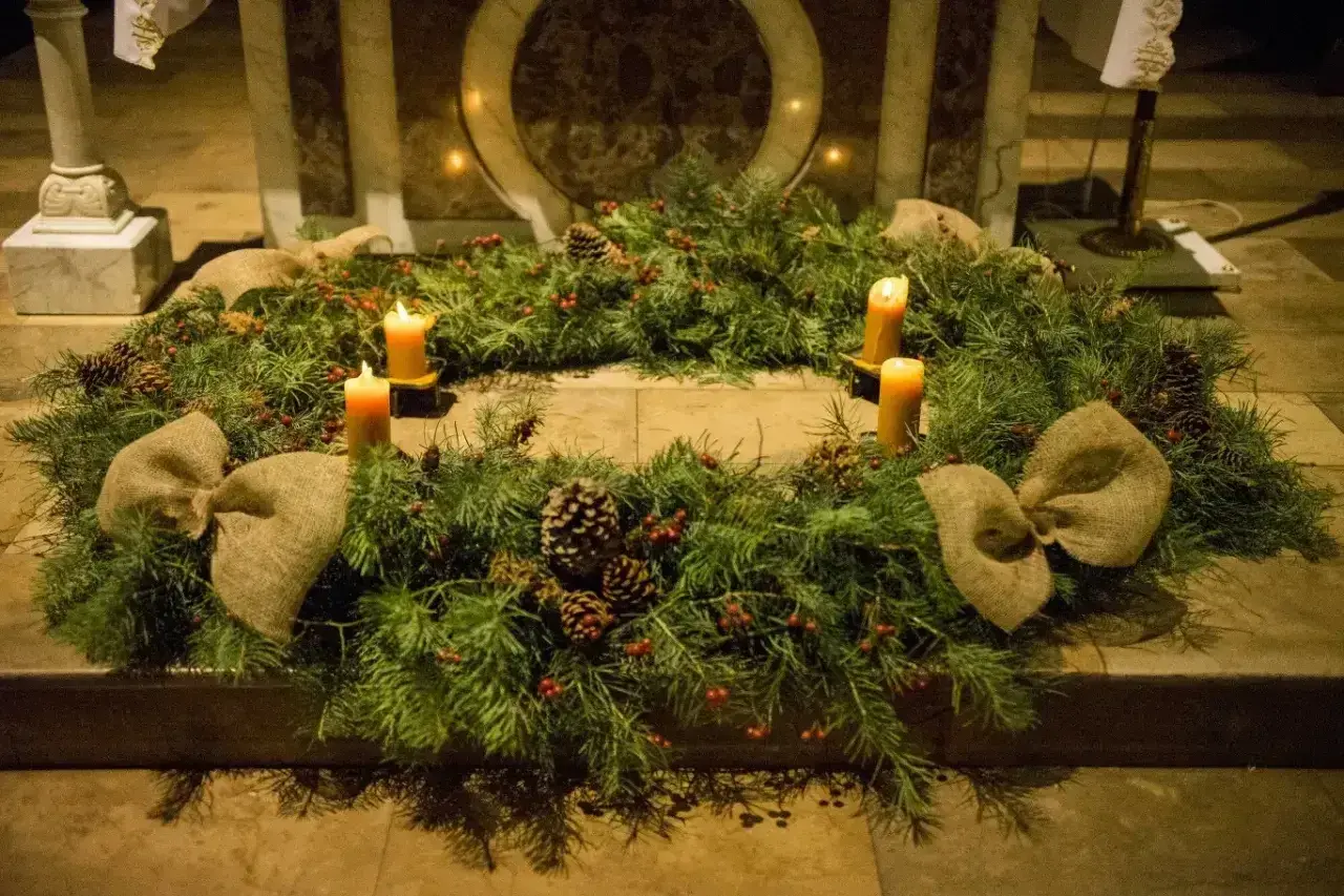 Wieniec adwentowy z czterema świecami, szyszkami i czerwonymi jagódkami, ozdobiony jutowymi kokardami. Czekamy na Roraty.