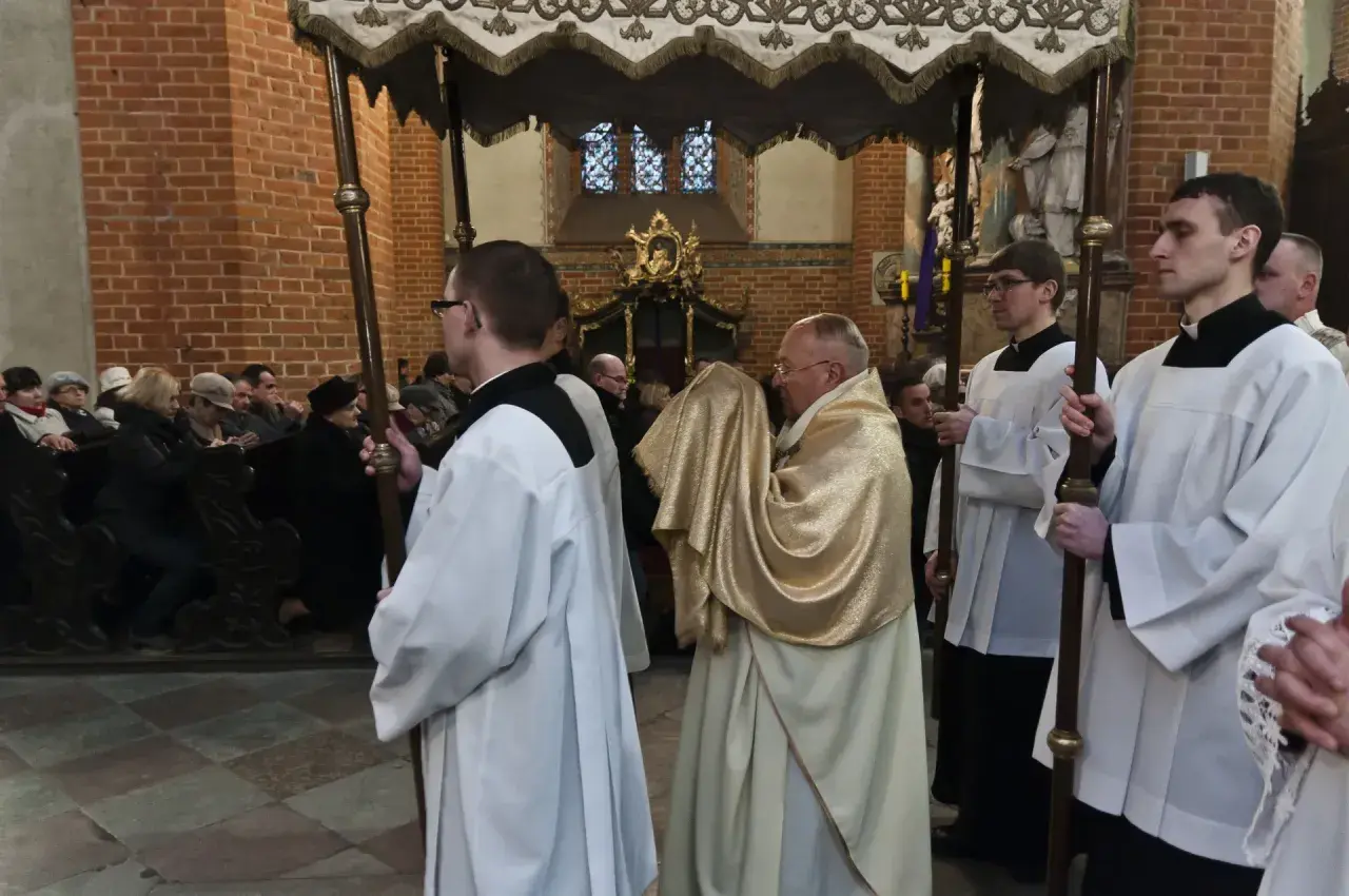 Uroczysta procesja w kościele, kapłan w złotej szacie niesie relikwie. To symboliczna rezurekcja.