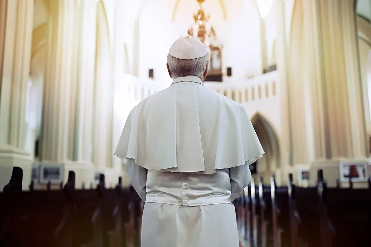 Papież w białej szacie i piusce stoi w kościele, przygotowując się do uroczystej beatyfikacji.