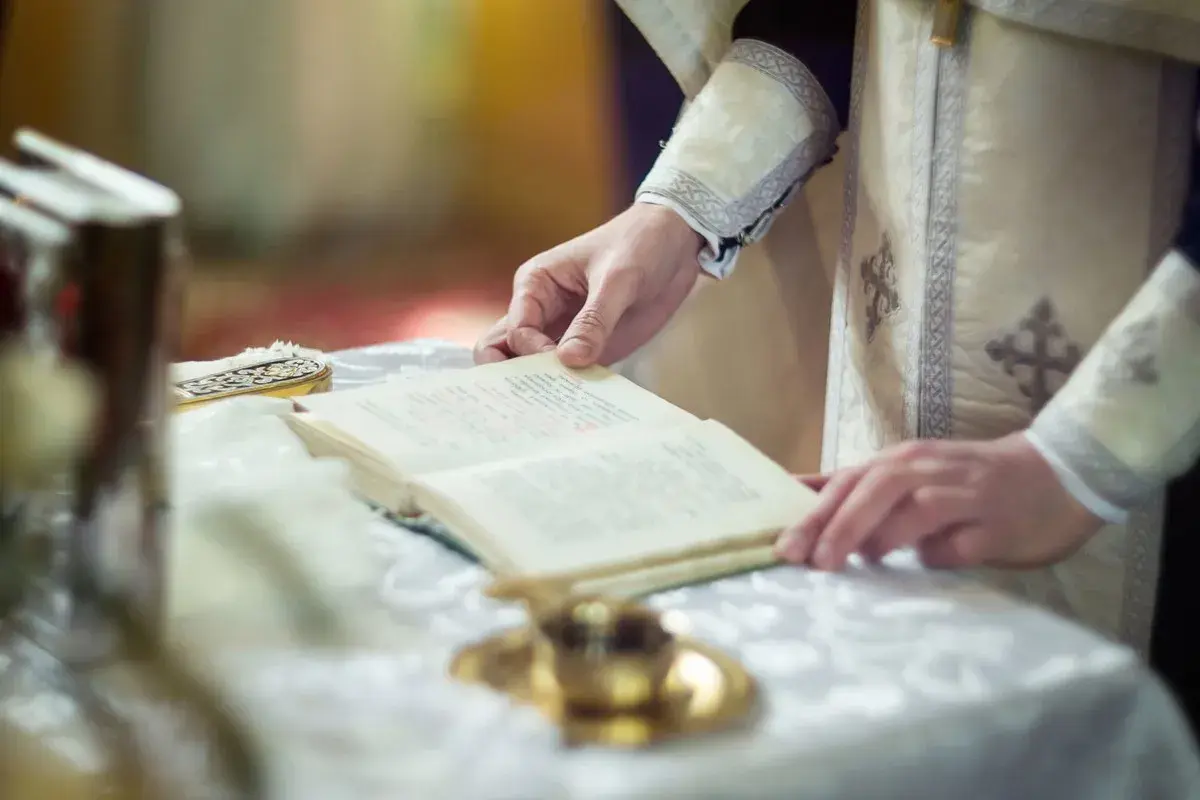 Dłoń duchownego trzyma księgę podczas nabożeństwa. Czas trwania rezurekcji jest nieznany, ale liturgia jest podniosła.