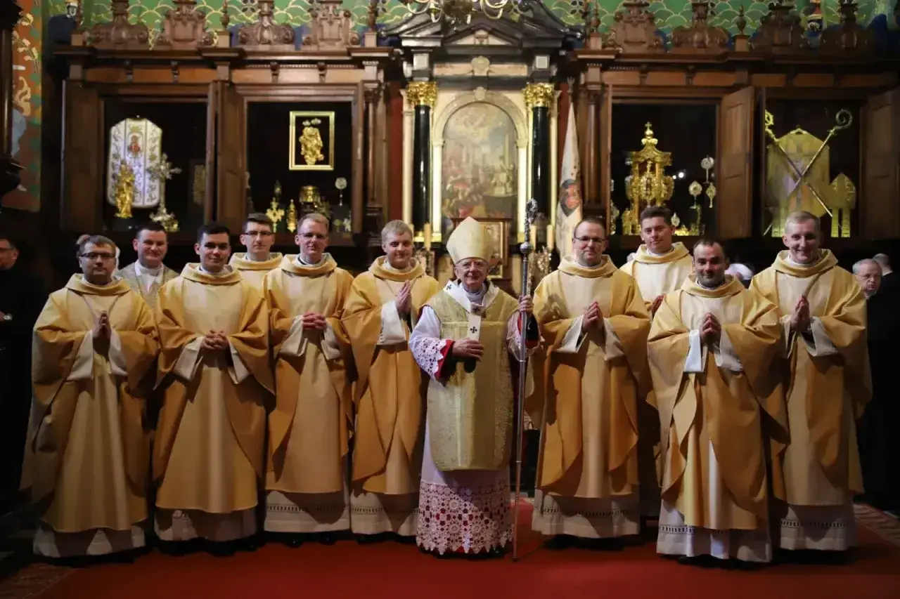 Biskup w otoczeniu młodych kapłanów w kościele.
