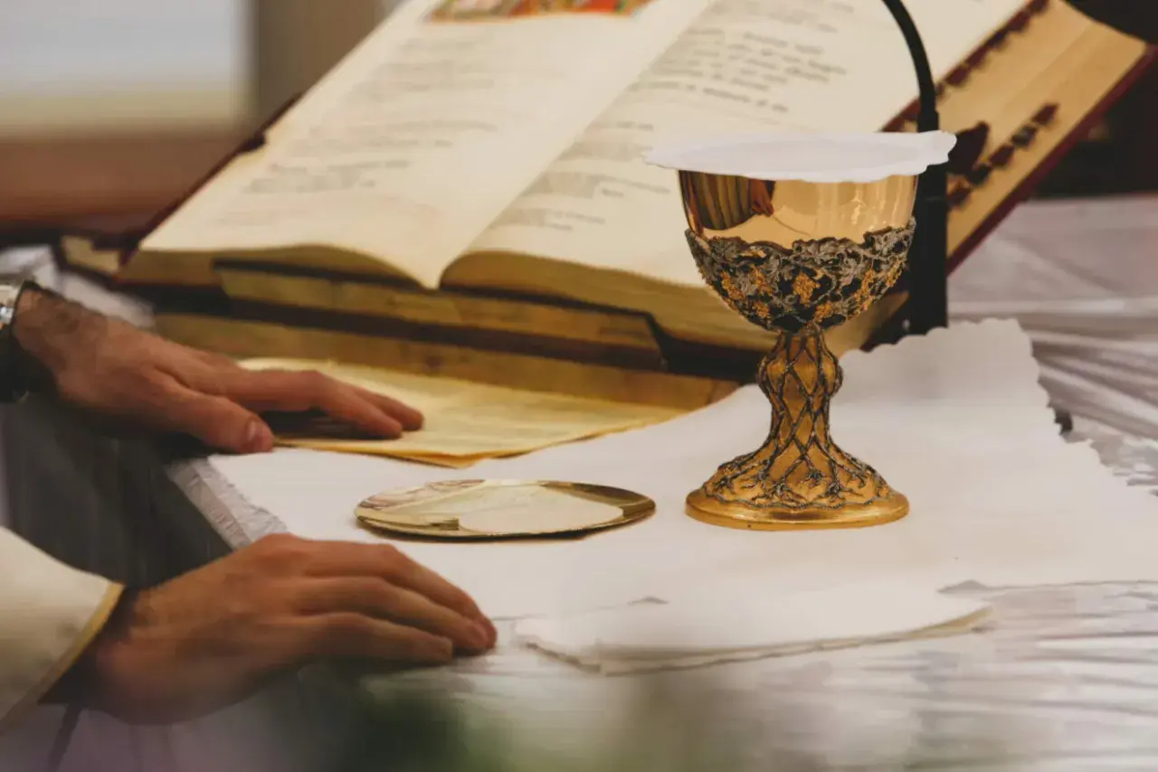 Złoty kielich i księgi liturgiczne na ołtarzu, przygotowanie do mszy. To moment, gdy wierni doświadczają cudu eucharystycznego.