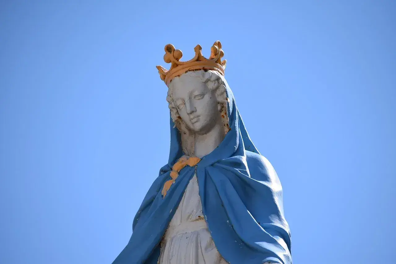 Posąg Matki Boskiej w koronie, symbolizujący czystość i idealizm, na tle błękitnego nieba.