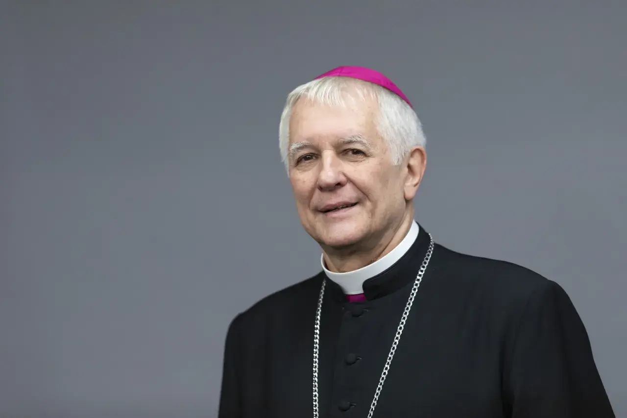 Uśmiechnięty biskup katowicki w stroju duchownym, z różowym zucchetto na głowie i srebrnym łańcuchem.