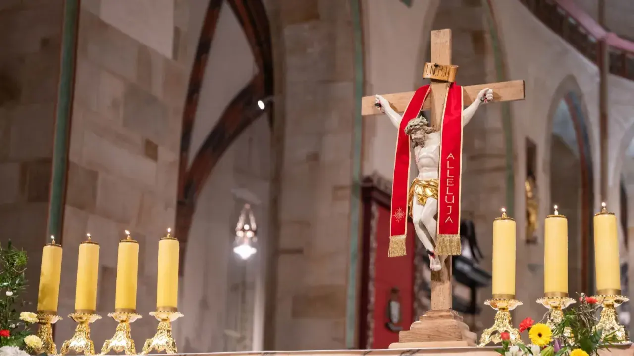Chrystus na krzyżu z czerwoną wstęgą "Alleluja". Obok płonące świece. 25 marca święto kościelne.