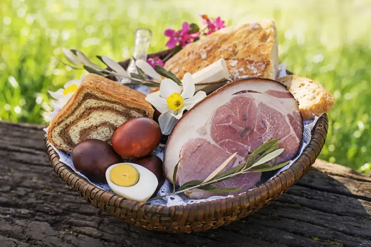 Koszyk z pieczonym mięsem, chlebem, jajkami i kwiatami. Czy w Wielką Sobotę można jeść mięso? Tradycyjnie nie, ale ten widok kusi!