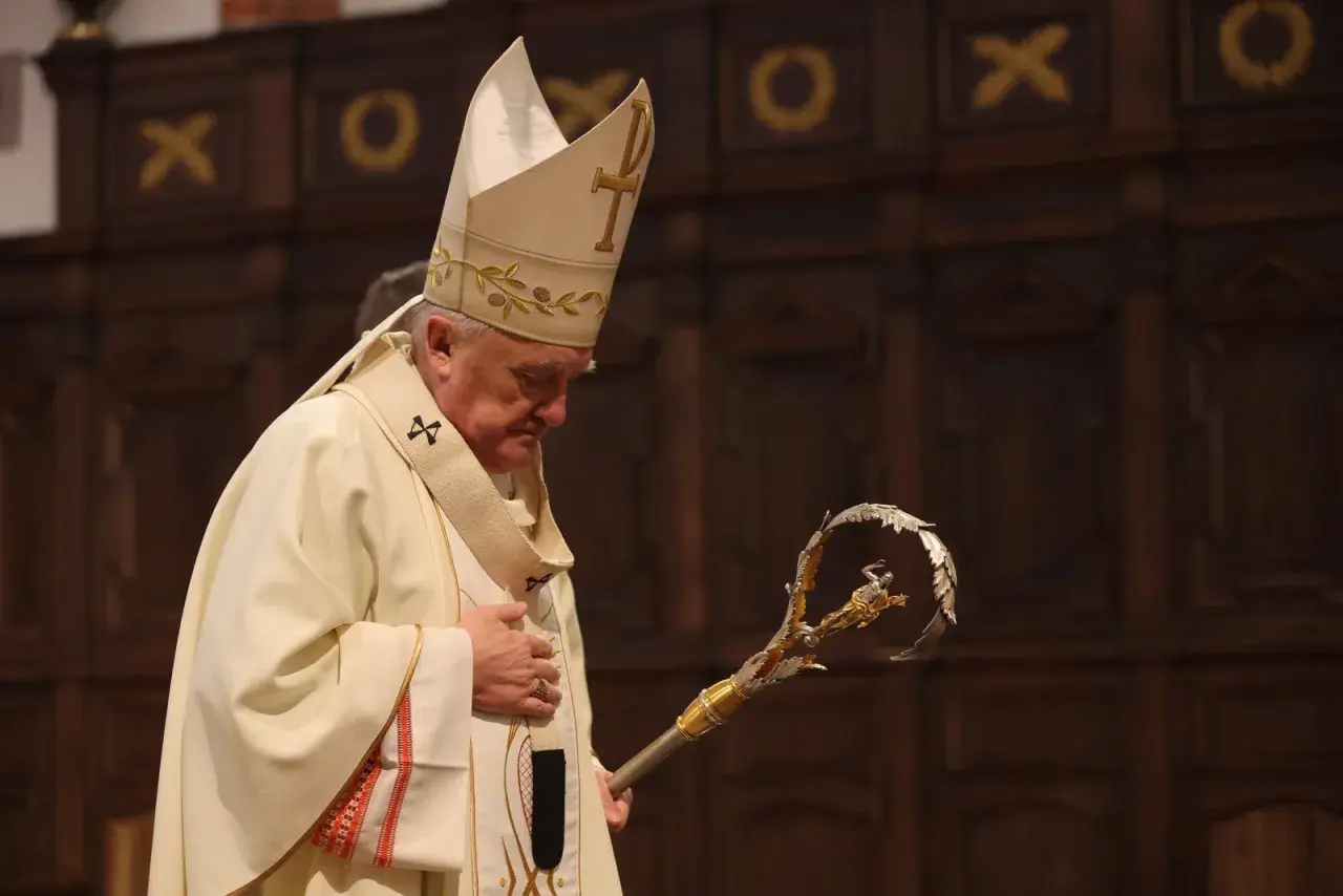 Biskup Nycz w białej szacie i mitrze z krzyżem, trzyma pastorał.