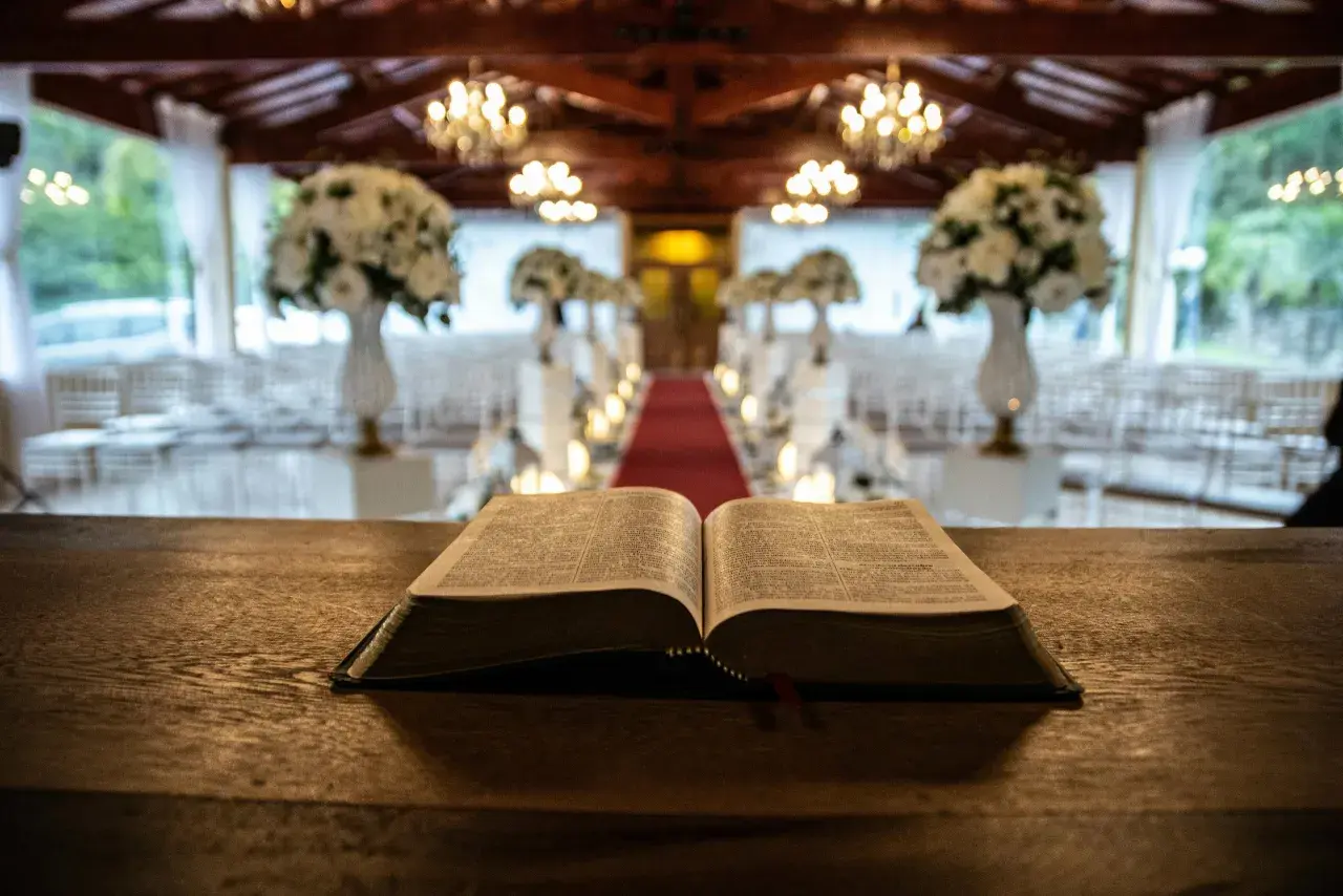 Otwarta Biblia na drewnianym stole, w tle udekorowana sala weselna. Symbolika 666 znaczenie w kontekście duchowym.