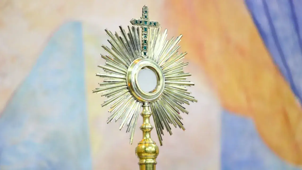 Monstrancja z hostią, symbol cudów eucharystycznych w Polsce, lśni na tle barwnego tła.