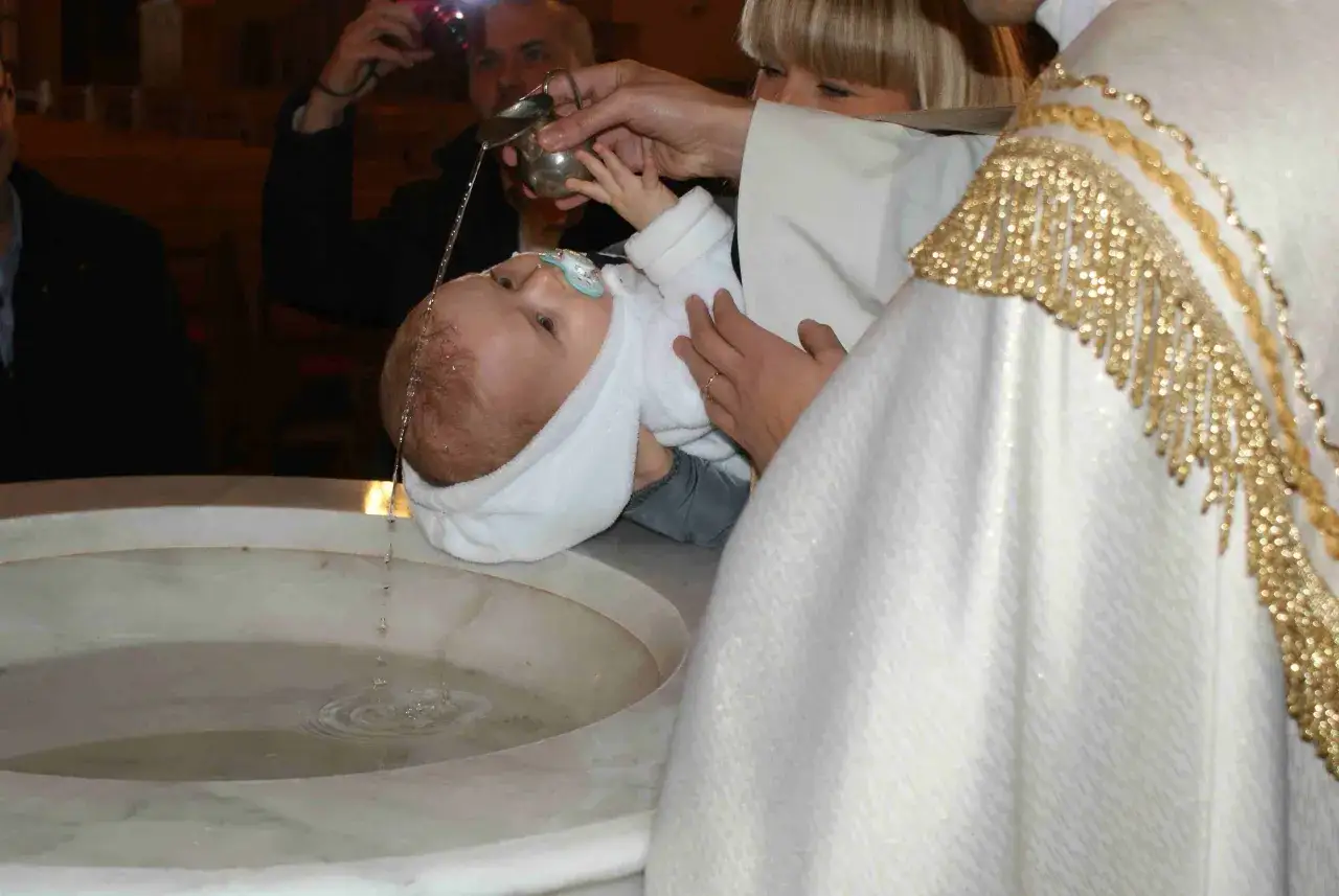 Chrzest dziecka w kościele. Kapłan polewa główkę malucha wodą święconą. Niech będzie pochwalony Jezus Chrystus!