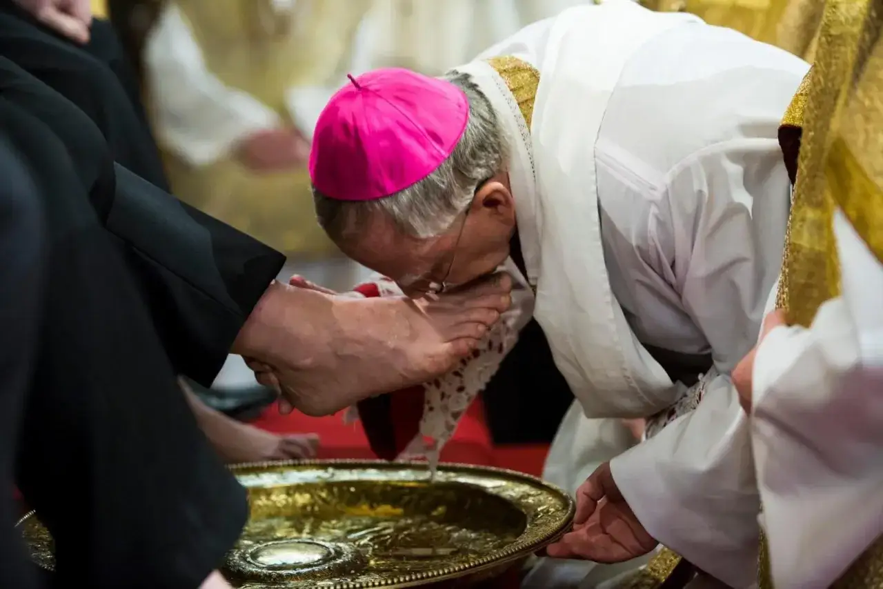 Biskup w różowym piusce całuje stopę klęczącego mężczyzny podczas obrzędu. To symbol pokory i służby, przypominający o tym, czy w Wielki Czwartek można jeść mięso.