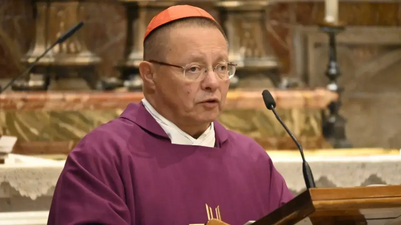 Biskup Ryś w purpurowej szacie i czerwonej piusce, z okularami, przemawia przy mikrofonie. Jego poglądy są wyrazem głębokiej wiary.