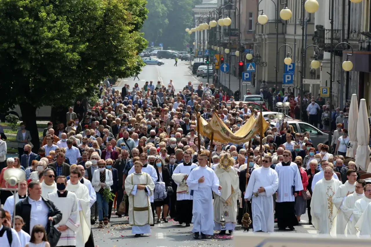 Tłum wiernych idzie ulicą w procesji. Wśród nich duchowni niosą baldachim i monstrancję. To wyjątkowe święta w czerwcu.