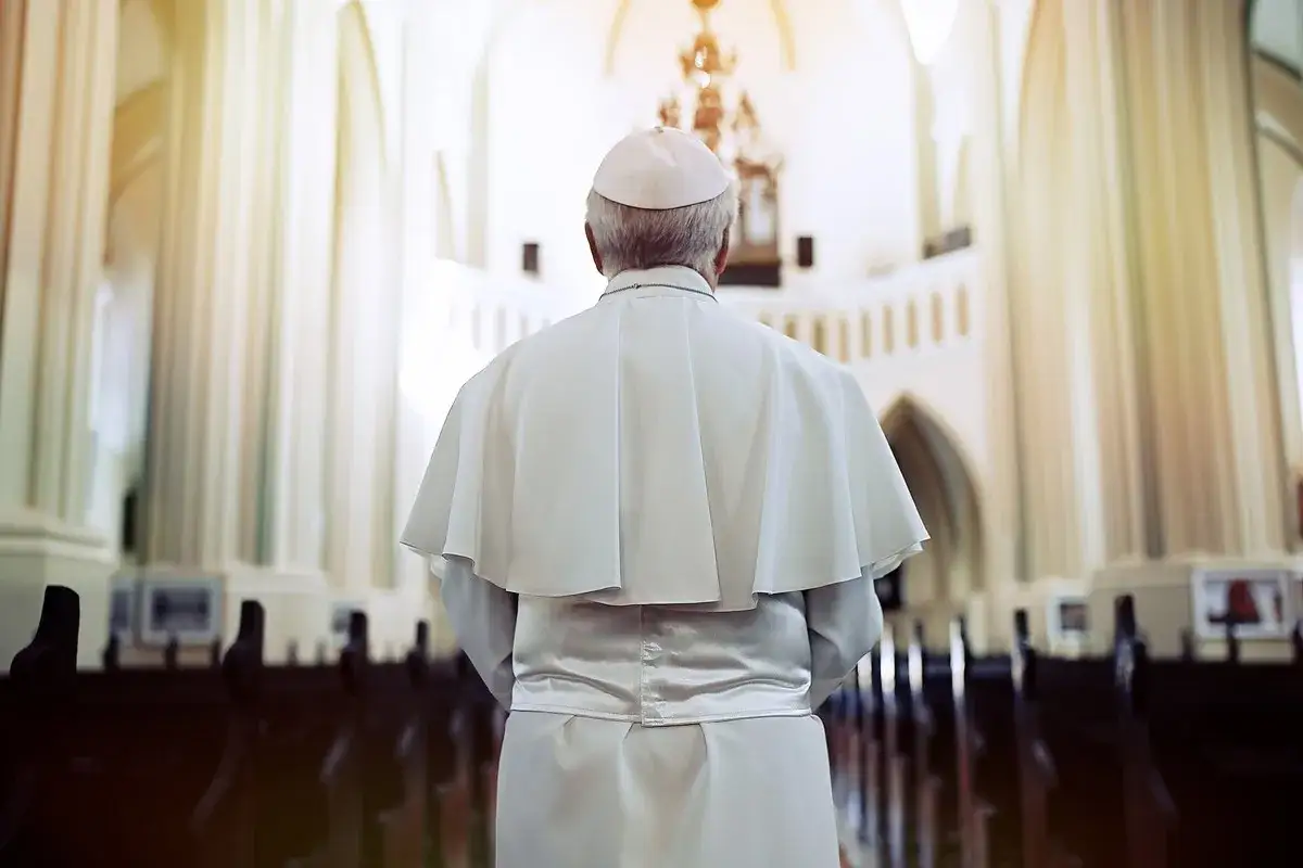 Papież w białej szacie i piusce stoi w kościele, przygotowując się do uroczystej beatyfikacji.