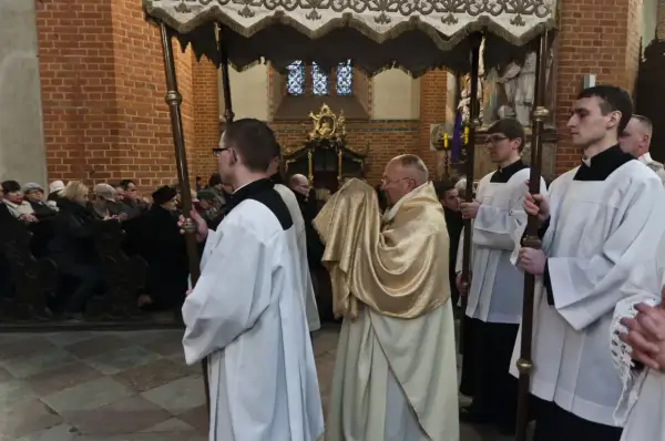 Uroczysta procesja w kościele, kapłan w złotej szacie niesie relikwie. To symboliczna rezurekcja.