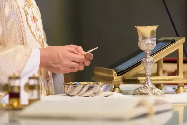 Kapłan trzyma opłatek, przygotowując się do Eucharystii. Co to jest Eucharystia? To sakrament.