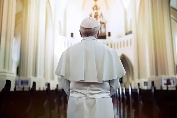 Papież w białej szacie i piusce stoi w kościele, przygotowując się do uroczystej beatyfikacji.