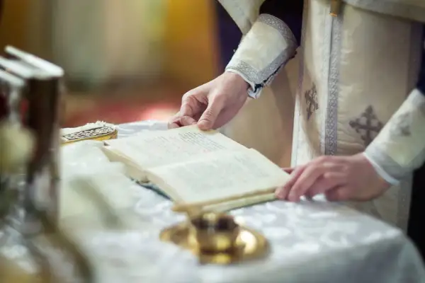Dłoń duchownego trzyma księgę podczas nabożeństwa. Czas trwania rezurekcji jest nieznany, ale liturgia jest podniosła.