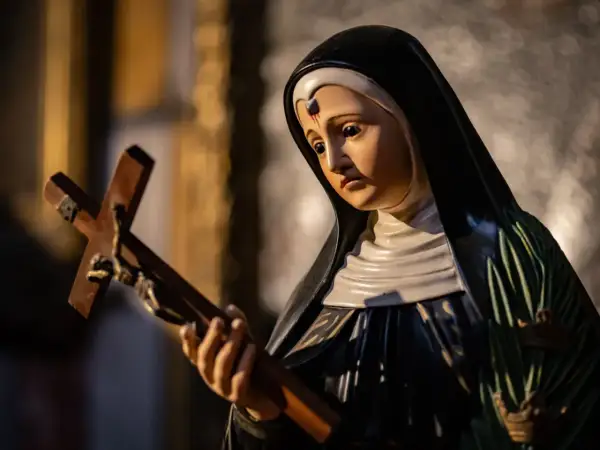 Figurka zakonnicy z krzyżem, symbol nadziei i anioł od spraw beznadziejnych, w świetle świec.