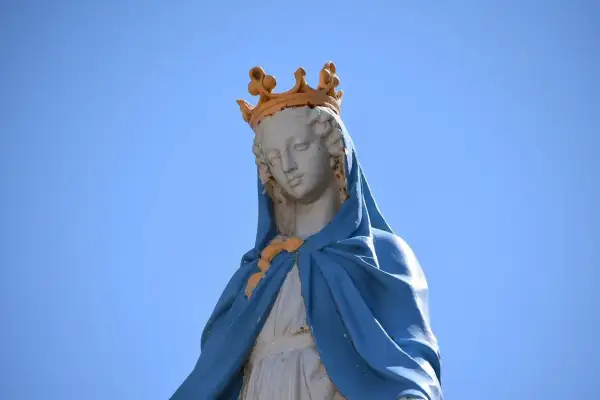 Posąg Matki Boskiej w koronie, symbolizujący czystość i idealizm, na tle błękitnego nieba.