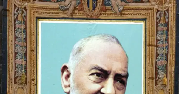 Portret Ojca Pio, jego ciało jest częściowo widoczne. Obraz ozdobiony jest bogatą ramą z motywami kwiatowymi i aniołkami.