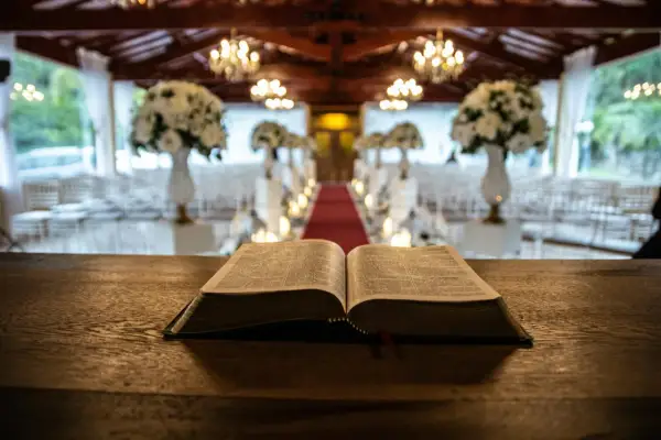 Otwarta Biblia na drewnianym stole, w tle udekorowana sala weselna. Symbolika 666 znaczenie w kontekście duchowym.